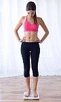 Young Healthy Girl On Weight Scales At Home Stock Photo