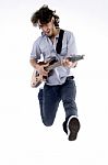 Young Male Jumping High Holding His Guitar Stock Photo