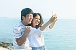 Young Man And Woman Take A Photo By Smart Phone At Sea Side Use Stock Photo