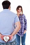 Young Man Hiding The Gift From Her Girlfriend Stock Photo