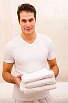 Young Man Holding Stack Of Fresh Towels Stock Photo