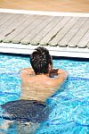Young Man Relaxing At The Edge Of The Swimming Pool Stock Photo