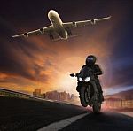 Young Man Riding Motorcycle On Asphalt Highways Road With High Speed And Jet Plane Flying Over Sky Stock Photo