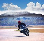Young Man Riding Motorcycle On Asphalt Road Against Mountain Hig Stock Photo