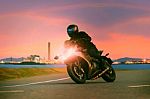 Young Man Riding Sport Touring Motorcycle On Asphalt Highways Against Beautiful Lighting Of Urban Industry Scene Use As Modern People Lifestyle And Holiday Activities Stock Photo