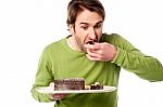 Young Man Tasting Chocolate Cake In Hurry Stock Photo