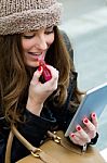 Young Woman Painting Her Lips With A Digital Tablet Stock Photo