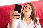 Young Woman Puckering While Taking Selfie On Sofa Stock Photo