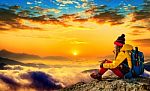 Young Woman Sitting On The Hill Of High Mountains At Sunrise Stock Photo