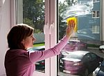 Young Woman Washing A Window Pane With Yellow Rag Stock Photo