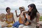 Younger Asian Woman Friend Vacation Relaxing Playing Guitar And Sing A Song On Sea Beach Stock Photo