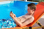 Youngster Operating Mobile Phone At Swimming Pool Stock Photo